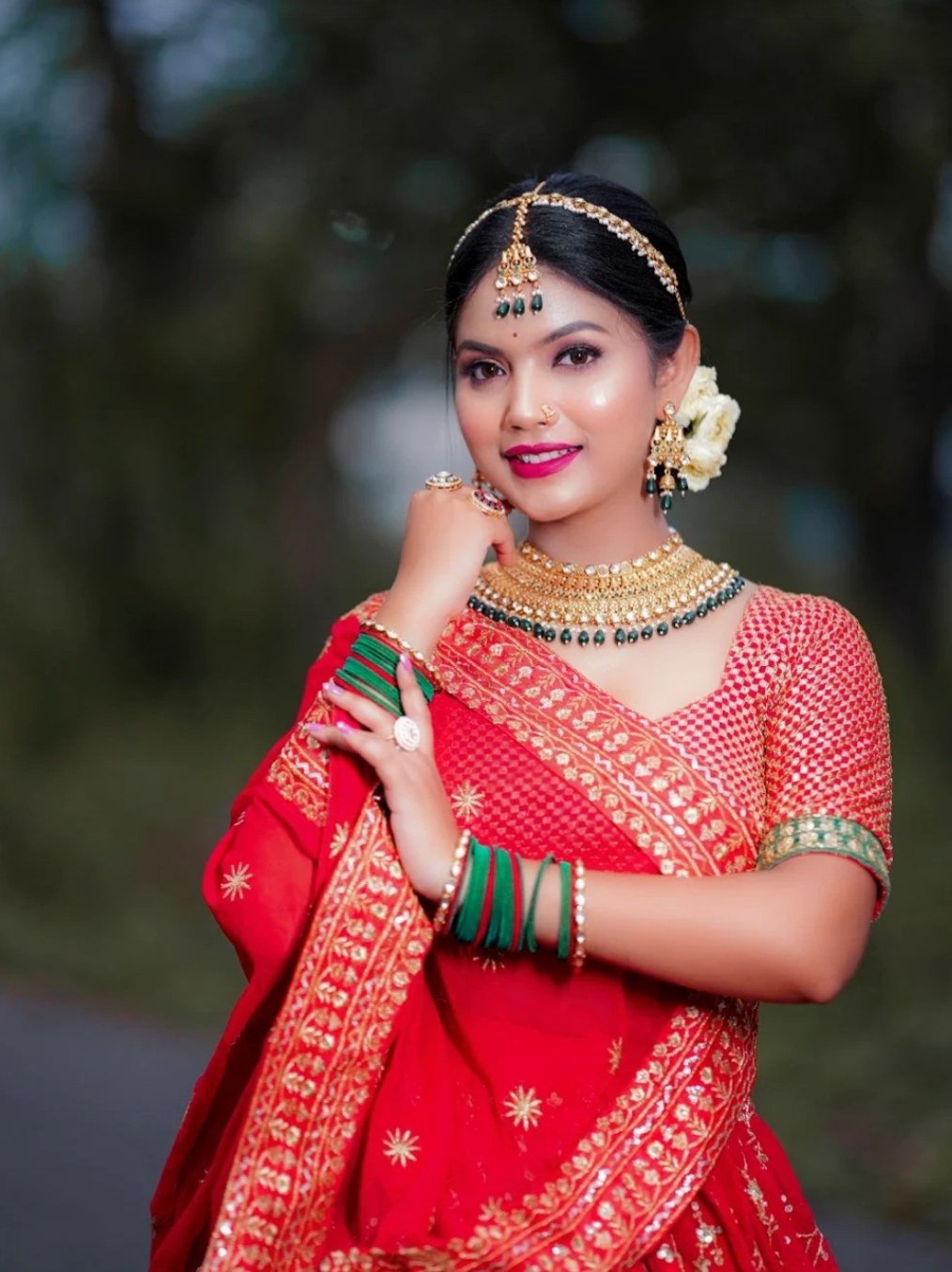 Bride in red sari showing bridal makeup and jewellery